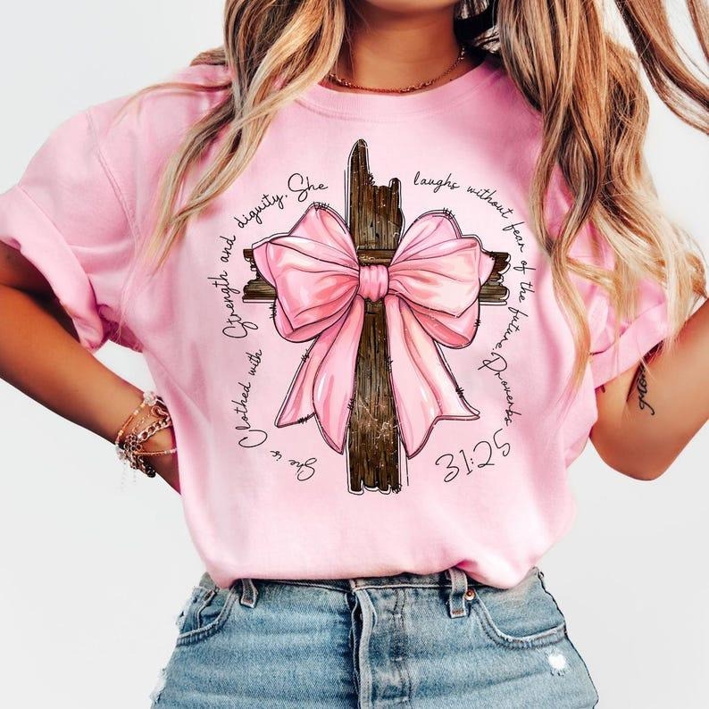 Proverbs She is Clothed with Strength Coquette Bow Light Pink Shirt, Preppy Design, Coquette Bow, Bible Verse, Christian Girls, Cotton, Crewneck, Graphic Tee
